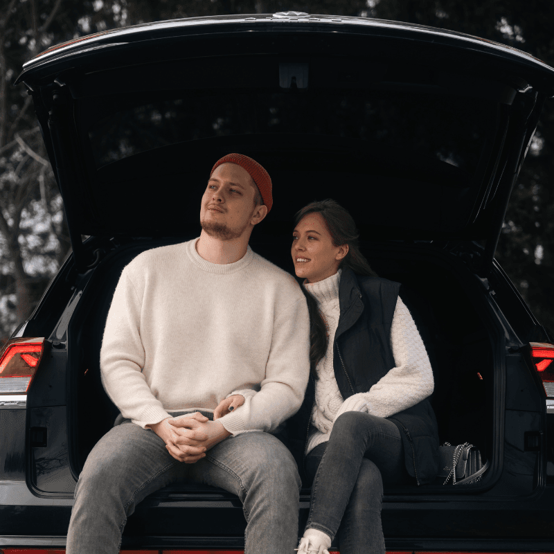 Couple sitting together in the open trunk of an SUV