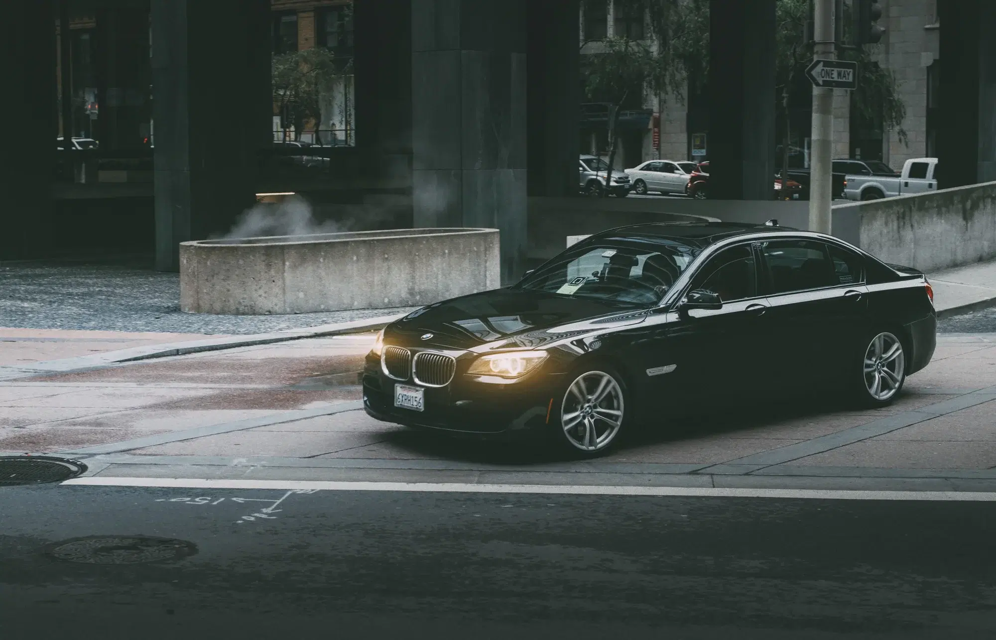 Black BMW sedan turning through a city intersection at dusk