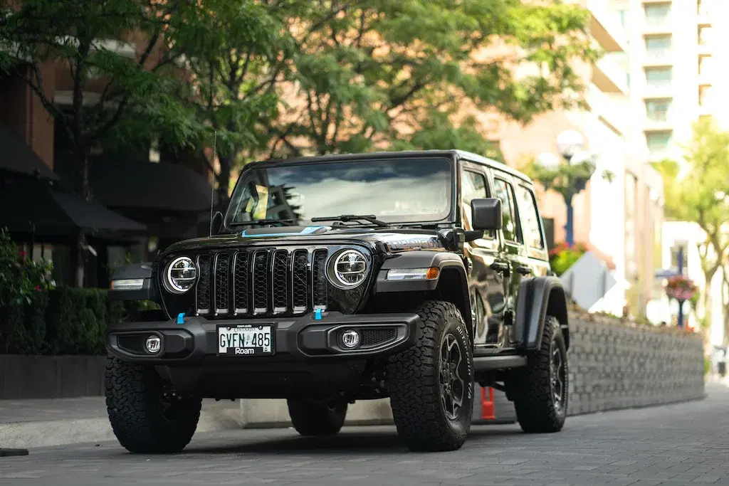 Black Jeep Wrangler Rubicon 4xe parked on a city street with buildings behind